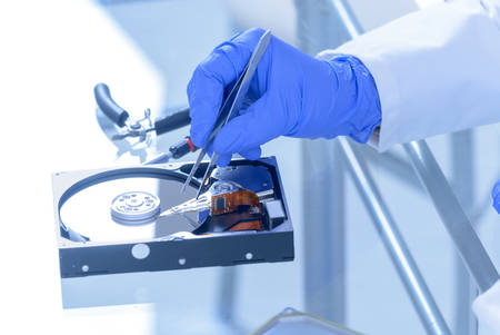 Service man fixing disk failure, hands protected with gloves.