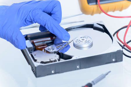 Service man fixing disk failure, hands protected with gloves.