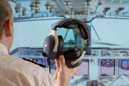 Captain holding his headphones in the cockipit of commercial airplaneの写真素材