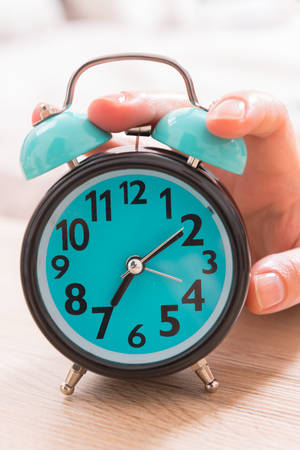 Hand on alarm clock trying to turn it offの写真素材