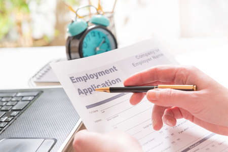 Blank employment application form in hands on a deskの写真素材