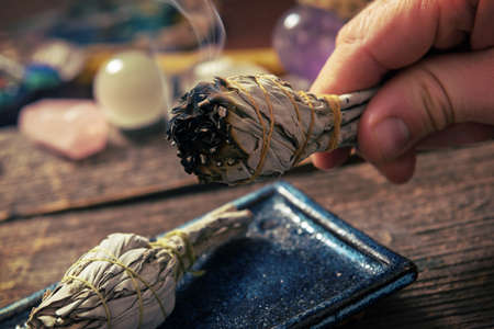 Man's hand with burning natural white sage incenseの写真素材