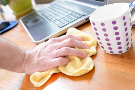 Hand cleaning desk with yellow cloth at homeの写真素材