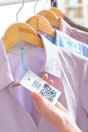 Woman's hand with a cloth label with QR code  in a shopの写真素材