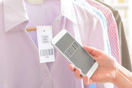 Woman scanning barcode from a label in a shop with mobile phoneの写真素材