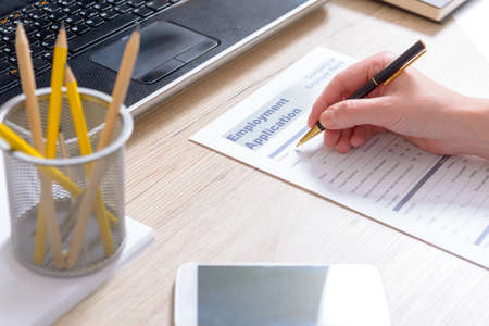 Filling in blank employment application form on a deskの写真素材