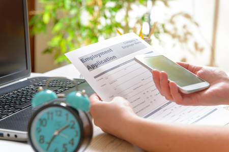 Blank employment application form in hands on a desk