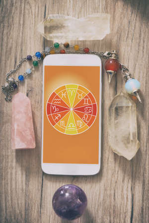 Zodiac signs and smart phone with crystal ball. Concept of modern astrology.の写真素材