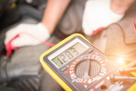 Car mechanic uses a multimeter to check car battery voltageの写真素材