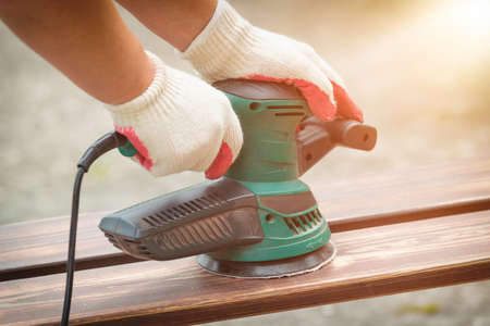 Sanding a wood with orbital sander outdoorの写真素材