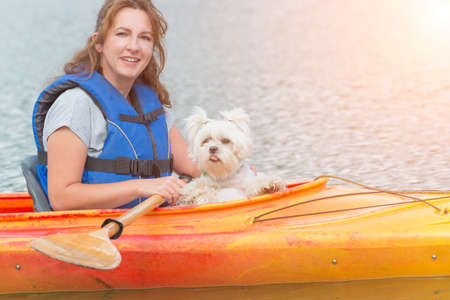 Beautiful woman and her dog on a kayakの写真素材