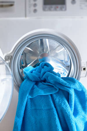 Modern washing machine loaded with blue towelの写真素材