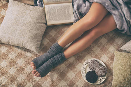 Woman with sweet gingerbread cookies, book lying on bed in the cozy room