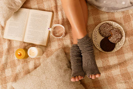 Woman with sweet gingerbread cookies, book and hot drink lying on bed in the cozy roomの写真素材