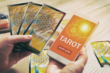 Tarot cards and smartphone with modern fortunetelling application on screen as a concept of psychic advisor or newest ways of divinationの写真素材