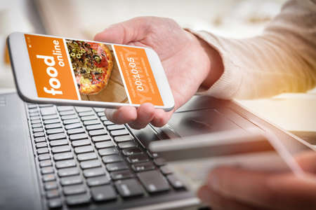 Ordering food online. Smartphone in hand and credit card in other. Concept of ordering food in office or workplace.の写真素材