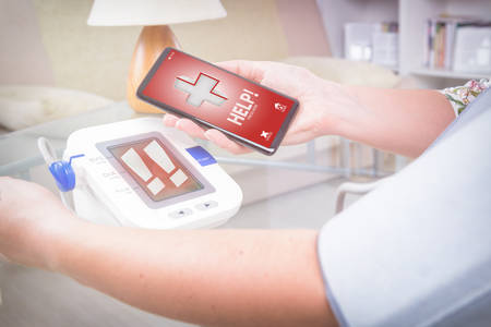 Woman measuring blood pressure at home and using simple user-friendly smart phone application to...