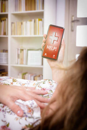 Woman holding her hand on the chest at home and using simple user-friendly smart phone application to call rescue team to prevent heart attackの写真素材