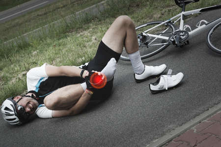 Bicycle accident. Biker holding his ankle.