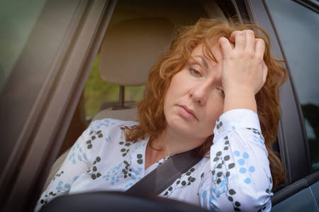 Bored woman sitting in a car in traffic jam looking through the open window.の写真素材