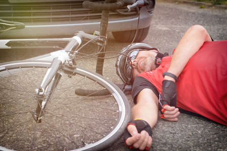 Cyclist lying on the road after an accident involving a car and a bicycleの写真素材