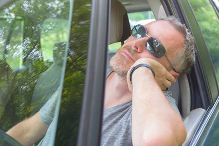 Man driver is resting in the car during a travel breakの写真素材