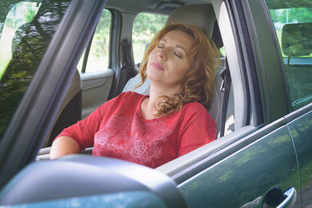 Woman driver is resting in the car during a travel breakの写真素材