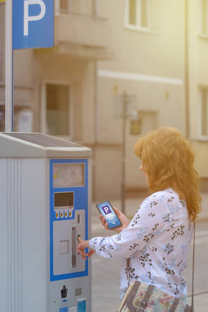 Woman using smartphone app to pay for parking in the paid parking zone in a cityの写真素材