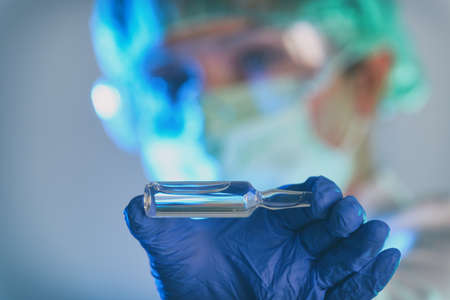 Scientist working in a laboratory holds an ampoule with a new vaccine in her hand