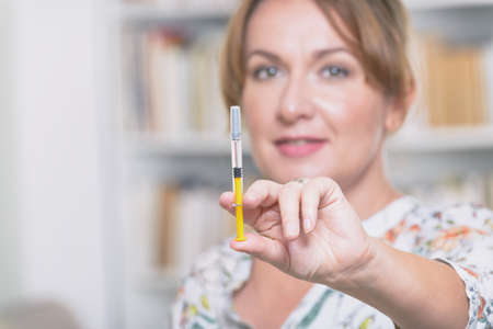 Woman is holding syringe with insulin or heparin in her hand at home