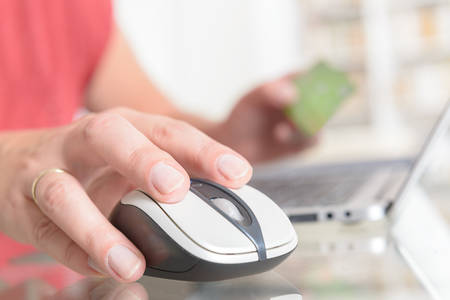 Woman's hand holding credit card over notebook and using it to pay online with it, concept of e-commers and online paymentの写真素材