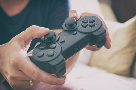 Mature woman or wife plays video game using the gamepad at home