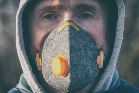 man wearing a real anti-pollution, anti-smog and viruses face mask; dense smog in airの写真素材