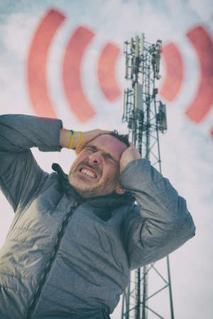 Man holding his head near the BTS. Harmful radiation from cellular network transmitters concept