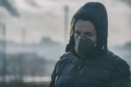 Woman wearing a real anti-pollution, anti-smog and viruses face mask; dense smog in air.
