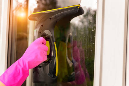 Cleaning windows with portable professional vacuum cleaner. Hand in protective gloveの写真素材
