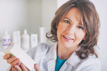 Portrait of a female pharmacist showing a medicine in the drugstoreの写真素材