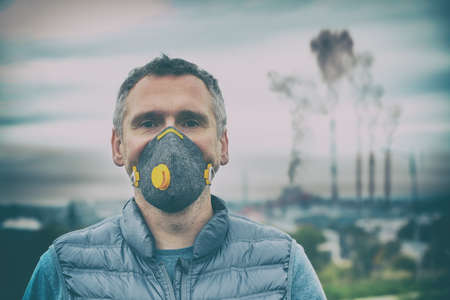 Man wearing a real anti-pollution, anti-smog and viruses face mask; dense smog in air.の写真素材