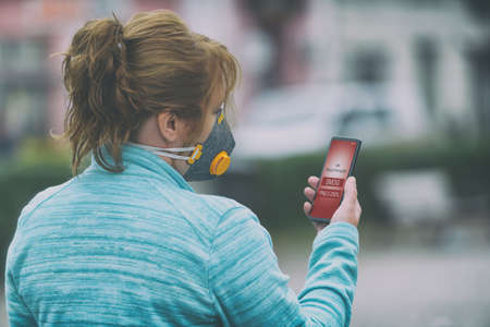 Woman wearing a real anti-pollution, anti-smog and viruses face mask and checking current air...
