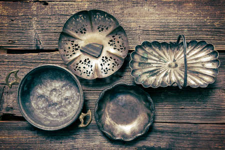 Old used silver and steel dishware on wooden boardの写真素材
