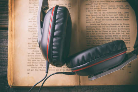 Headphones on the old book. Concept of listening to audiobooks.の写真素材