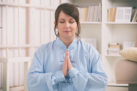 Beautiful woman doing qi gong tai chi exercise at home