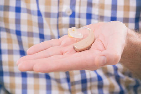 Man showing deaf aid in hand