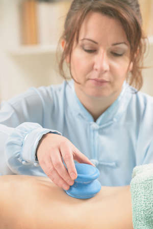 Therapist doing traditional chinese cupping therapy on her patient