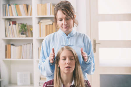 Professional Reiki healer doing reiki treatment to young womanの写真素材