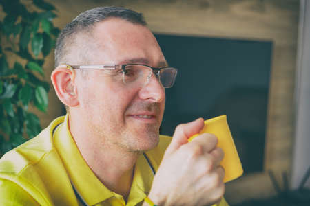 Relaxed hearing impaired man at home. Hearing aid in his ear.
