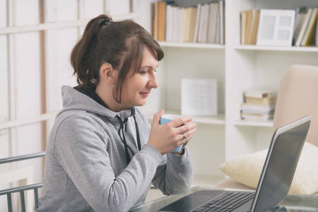 Hearing impaired woman working with laptop and talking on the phone at home or office