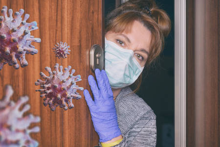 Woman wearing a protective face mask opening doors of her home because of an epidemic of corona virus covid-19. Home quarantine and self isolation conceptの写真素材