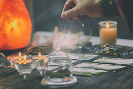 Fortune teller holding a pendulum over tarot cardsの写真素材