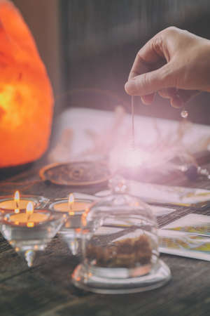 Fortune teller holding a pendulum over tarot cardsの写真素材